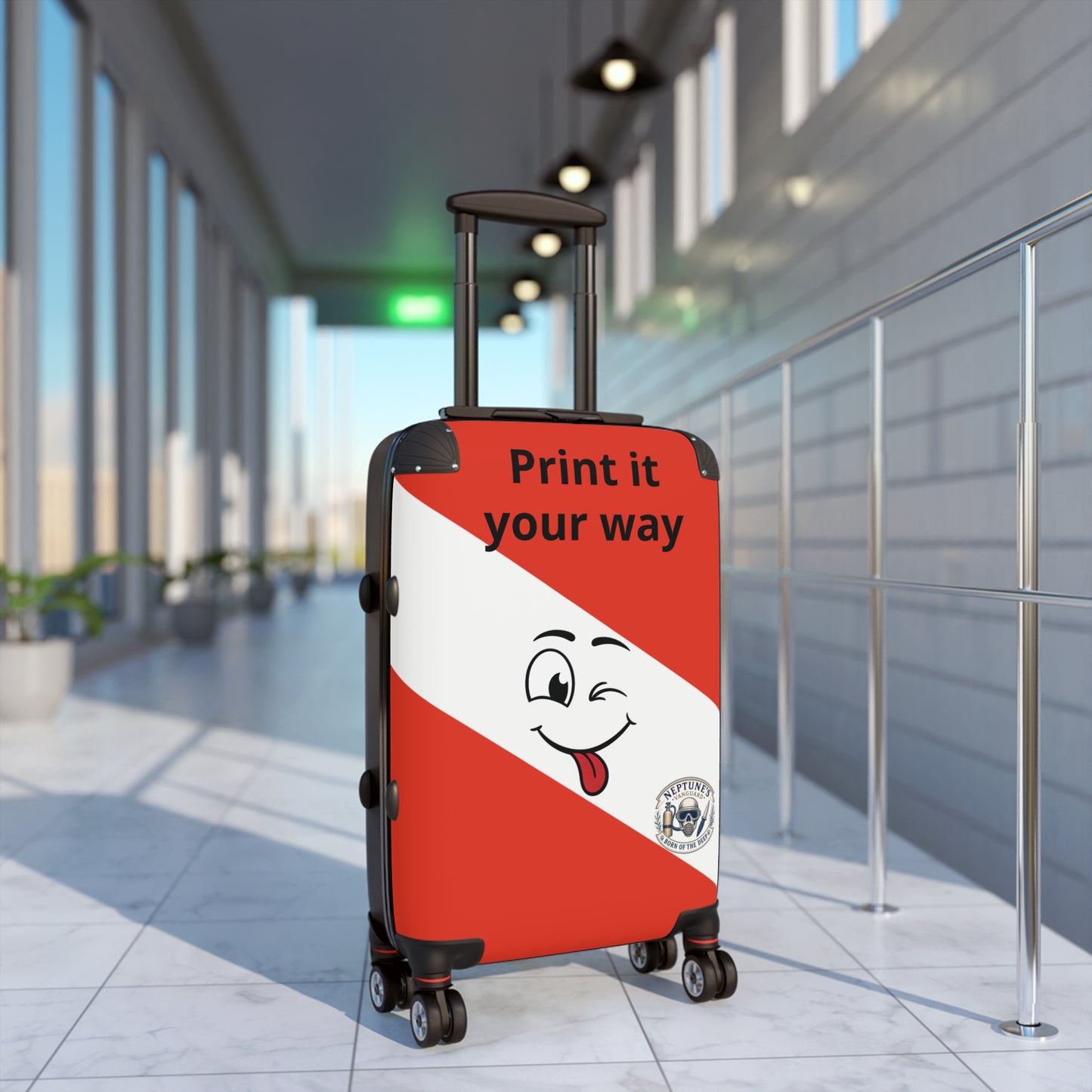 A hard-shell rolling suitcase stands in a modern airport terminal corridor. The suitcase has a red and white diagonal split design with a cartoon face and the text 'Print it your way' on the front.
